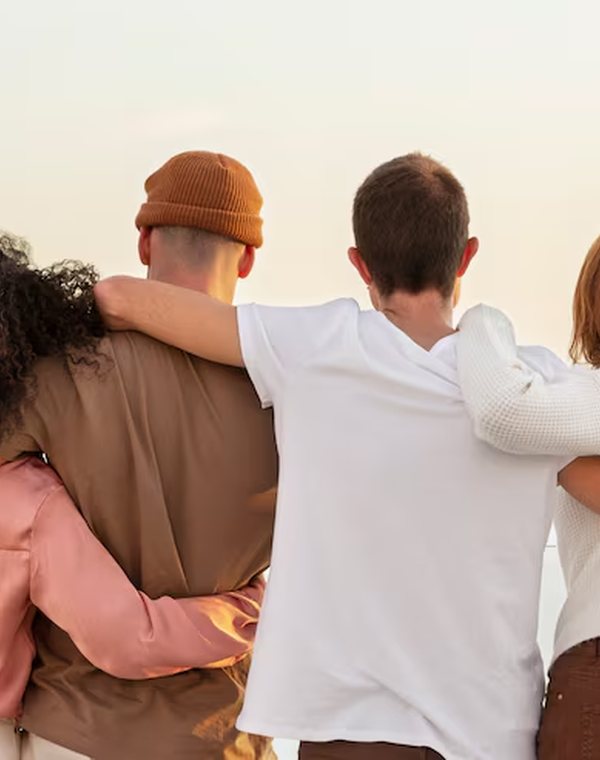 Amigos adultos abraçados, de costas, olhando o mar
